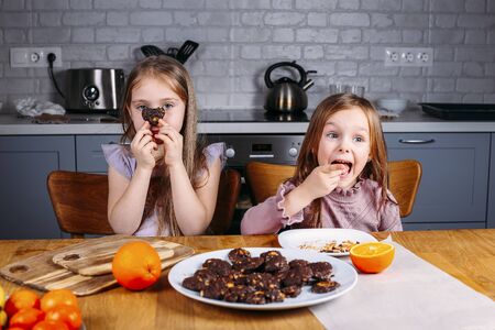 Young small girls eating biscuits at home. Playing and feeding themselfsの写真素材