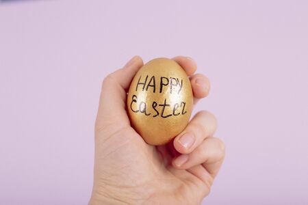 Hand holding gold easter egg with text Happy Easter. Toned pictureの写真素材