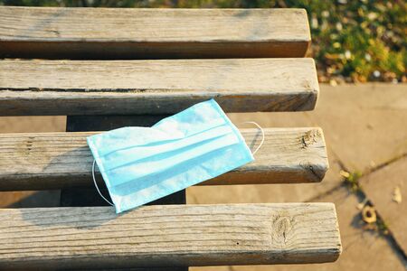Protective face mask on wooden bench. Typical 3-ply surgical mask to cover the mouth and nose. Procedure mask from bacteria. Protection concept.の写真素材