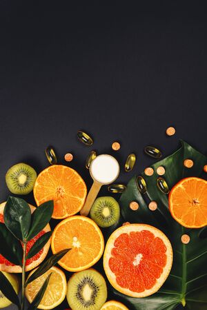 Multivitamins and supplements with fresh and healthy fruits on black background. Collagen. Fish oil capsuls.の写真素材