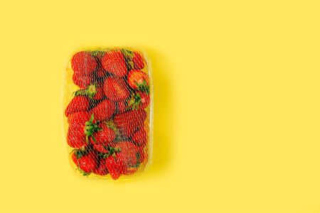Fresh trawberries in plastic box on yellow backgroundの写真素材
