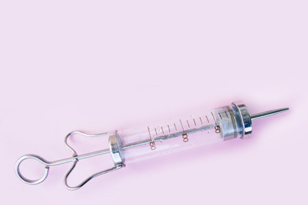 Old glass syringe on pink background.の写真素材