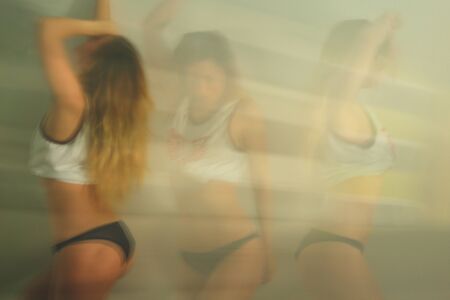 Blur motion. Young sexy woman dancing at home. Blurred imageの写真素材