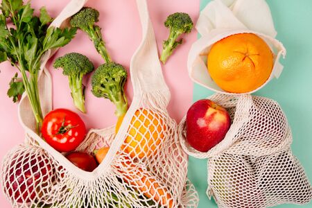 Top view of mesh shopping bag with organic eco vegetables on color background. Caring for the environment and the rejection of plastic conceptの写真素材