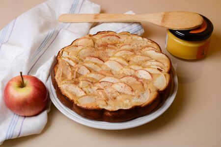 apple pie (charlotte) on a table close-up with a jar of honey and an appleの写真素材