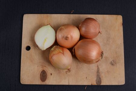 chopped onions with a knife on a cutting board on a black backgroundの写真素材