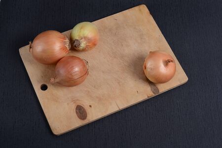 chopped onions with a knife on a cutting board on a black backgroundの写真素材