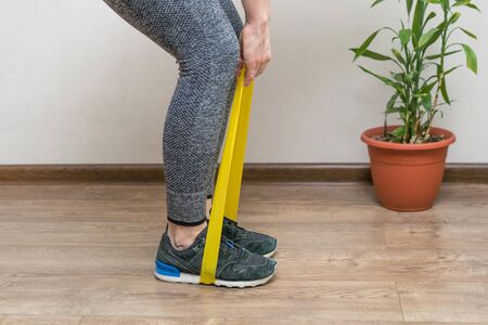 girl doing fitness at home, with dumbbells and a sports tapeの写真素材