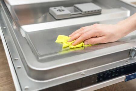 open dishwasher with clean plates, cups and forks inside, close upの写真素材