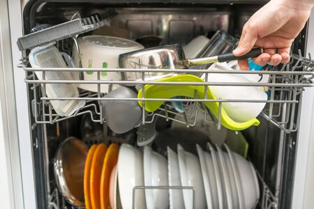 open dishwasher with clean plates, cups and forks inside, close upの写真素材