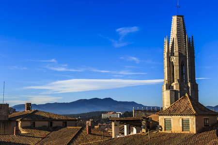 View from Girona Cathedra of Collegiate Church of St. Felix spire and mountains of Puig de la Banya del Boc in the distanceの写真素材