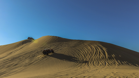 Sand dunes and buggies against clear blue sky at Huacachina, Peruの写真素材