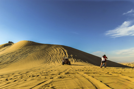 Huacachina, Ica, Peru - Jan 2015: Sand dune buggy racing down the slope as tourists move aside to avoid accidentのeditorial素材