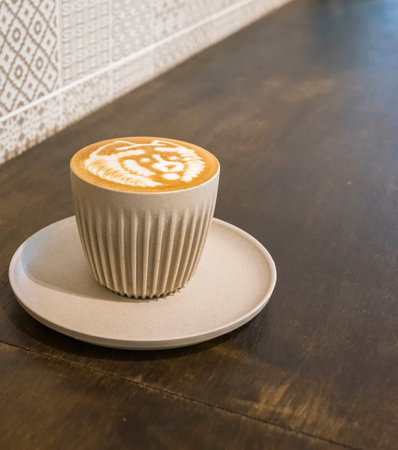 Freshly brewed latte in a beige porcelain coffee cup in a cafeの写真素材