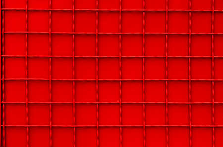 Texture of red checkered metal fence. Red metal sheet with gauze for background. Urban element of a red metal fence with square weave.の写真素材