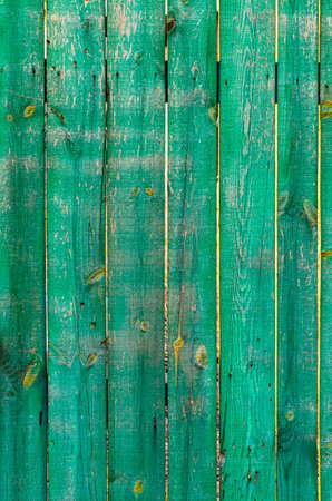 Old cracked painted green wooden fence with slits. Rough outdoor wooden textureの写真素材