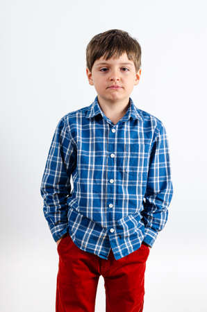Studio portrait of sad boy keeping hands in pockets of his red pants. Human face expressions, emotions and feelingsの写真素材