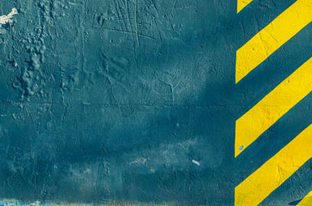 Blue painted wall with yellow stripes. Texture of rough surface of painted wall.の写真素材