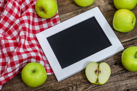 Ripe green apples with white frame for text on an old wooden table. Summer harvest of aromatic apples. Useful fruits on wooden background. Top view, close up.の写真素材