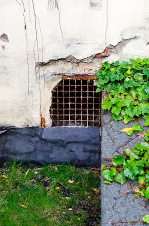 Desolate fragment of wall with latticed window. Part of bilding with basement windowの写真素材