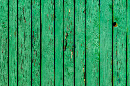 Old cracked painted green wooden fence with slits. Rough outdoor wooden textureの写真素材