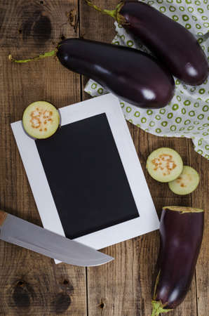 Cutting eggplants with knife and frame for writing. Vegetable for cooking and empty place on frame.の写真素材