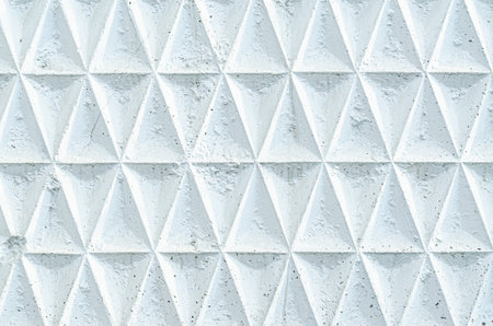 White paint concrete fence with triangular pattern. Texture of rough surface of old wall with...