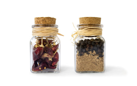Two glass jars with red and black peppers closed with a cork lid. Set of spices in glass jars on a...