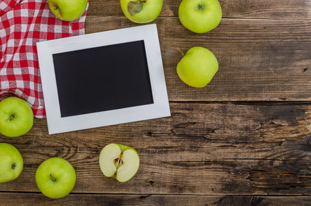 Ripe green apples with white frame for text on an old wooden table. Summer harvest of aromatic apples. Useful fruits on wooden background. Top view, close up.の写真素材