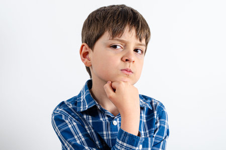 Handsome boy is wearing in plaid shirt thinking about something and puts his hand on the chin. Boy looking away isolated on white background.の写真素材