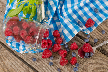 A jar of raspberries crumbled on an old wooden table. Fresh food for a healthy life and energy....