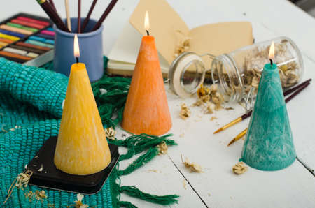 Set of burning candles on light background. Melted wax candles with elegant conic original form burning at holiday white table. Festive mood and atmosphere.の写真素材