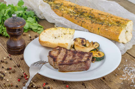 Grilled juicy barbecue steak with peace of bread and fried marrow on a white plate. Prepared fresh food for breakfast, lunch or dinner. Lots of meat energy for good nutrition.の写真素材