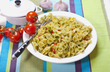 Delicious pasta with pesto sauce in a plate and a sprig with cherry tomatoes. Nutritious fresh food for the whole family. Kitchen recipes for hearty meals.の写真素材