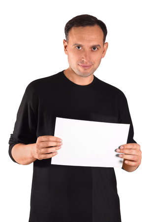 Confident man in black clothes holding blank white sheet in his hands. Studio shot of a serious man posing for the camera. Unique male emotions with different poses and objects.の写真素材