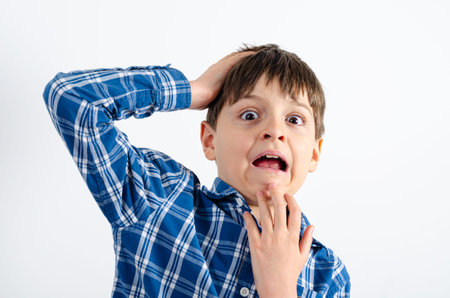 Portrait of a frightened boy who wears plaid shirt, isolated on white background. Kid with afraid...