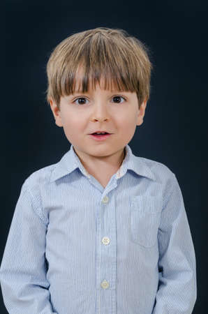 Portrait of a little boy with open mouth. Smart and tidy child on training in a striped shirt. Early childhood education for serious kids.の写真素材