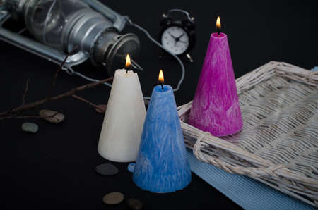 Three burning candles on dark background. Melted wax candles with elegant conic original form burning at holiday table. Festive mood and atmosphere.の写真素材