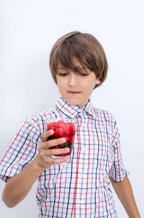 Teenage boy in a plaid shirt grabbed watermelon smoothie with his hand. Useful berries and fruits for children of any age. Happy children drink vitamin smoothies in summer.の写真素材