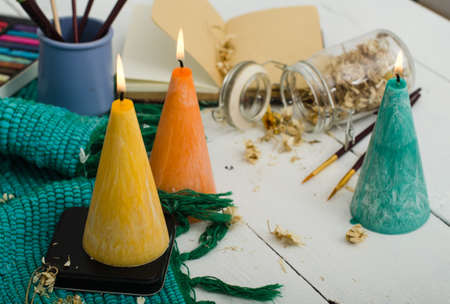 Set of burning candles on light background. Melted wax candles with elegant conic original form burning at holiday white table. Festive mood and atmosphere.の写真素材