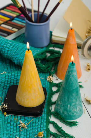 Set of burning candles on light background. Melted wax candles with elegant conic original form burning at holiday white table. Festive mood and atmosphere.の写真素材