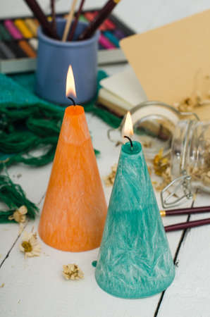 Set of burning candles on light background. Melted wax candles with elegant conic original form burning at holiday white table. Festive mood and atmosphere.の写真素材