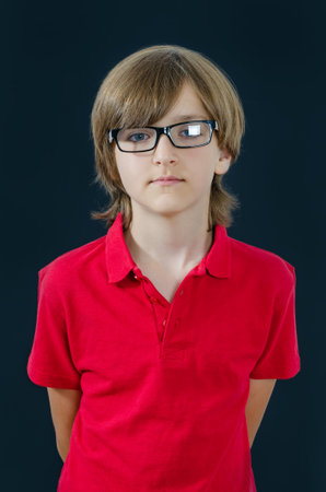 Teenager in red t-shirt and glasses has serious look. Smart and tidy child on training in a red t-shirt. Quality childhood education for serious kids.の写真素材