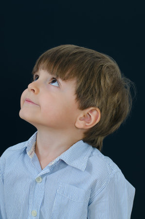 Portrait of a little boy looking up and side. Smart and tidy child on training in a striped shirt....