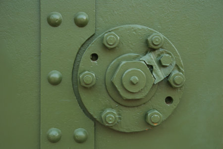 Metal part of the military vehicle painted in green protective color. Nuts and bolts, like metal rivets holding time itself together, protruded from its surface.の写真素材