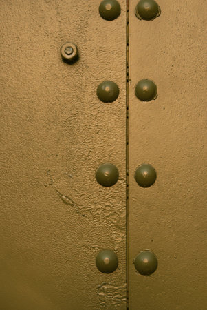 Metal part of the military vehicle painted in green protective color. Nuts and bolts, like metal rivets holding time itself together, protruded from its surface.の写真素材