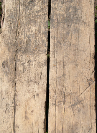 Old cracked weathered wooden fence with slits. Rough natural outdoor wooden texture. Vintage private property with aged damaged structure. It sunny day in the garden.の写真素材