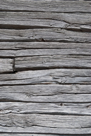 The gray vintage wooden wall of an ancient house, made from sturdy logs weathered by time. Each log, etched with the marks of seasons past, forms a mosaic of textures.の写真素材