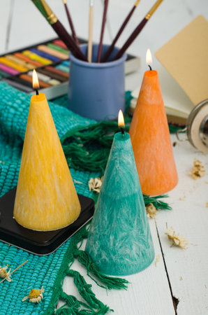 Set of burning candles on light background. Melted wax candles with elegant conic original form burning at holiday white table. Festive mood and atmosphere.の写真素材