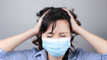 Woman wearing protection face mask against virus. Cannot hear. Woman in a mask closing her ears. Medical mask, Close up shotの写真素材